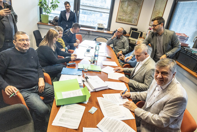 Lidé sedící u velkého pracovního stolu