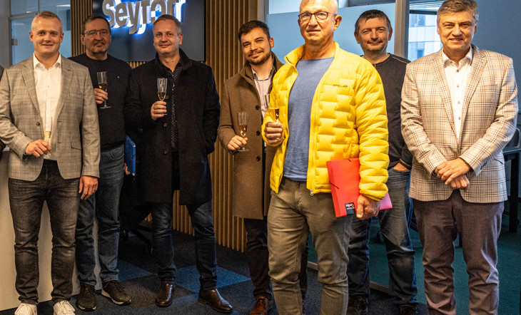 Skupina lidí uvnitř budivy hledící do foťáku